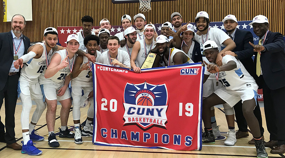 Baruch stands with the trophy and the banner for the CUNYAC tournament championship. 