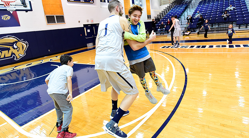 Steve Valencia-Biskupiak plays with two of his four kids on the floor for Gallaudet before his team's game. (Gallaudet athletics photo)